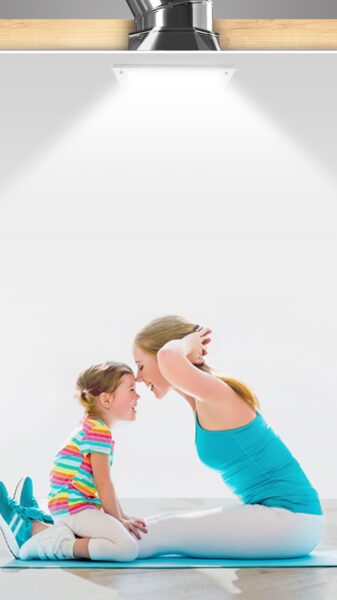 Solatube skylight installation with natural light streaming over mother and daughter doing yoga